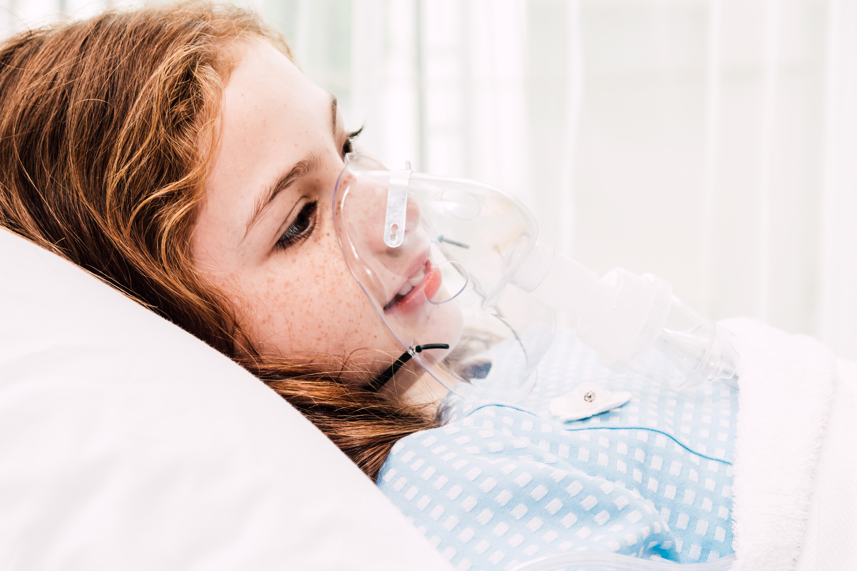 Girl in hospital bed with oxygen mask