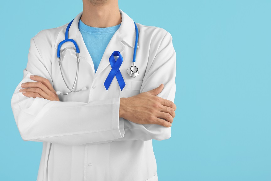 Doctor with arms crossed and blue ribbon on medical coat
